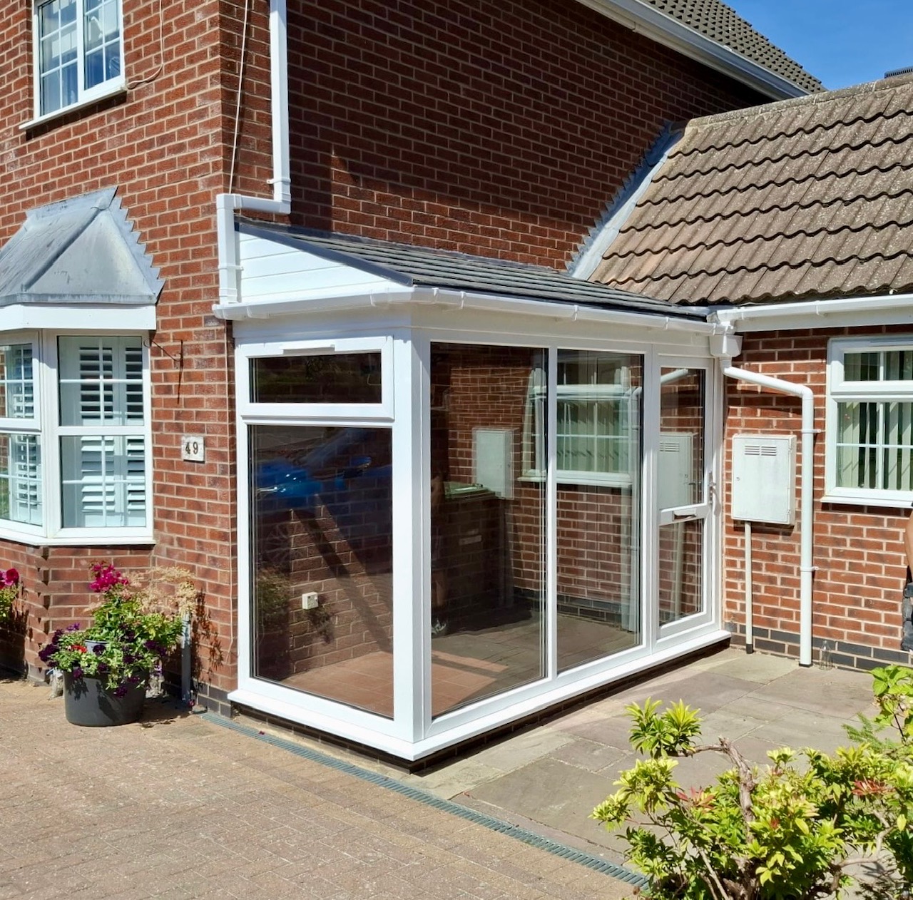 New white uPVC porch with composite tiled roof installed in Bushby