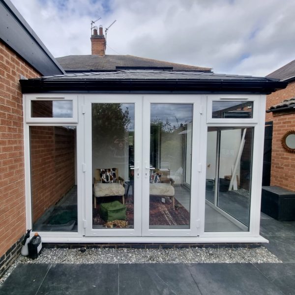 New conservatory installation with white uPVC windows and French doors, topped with a high-performance WARMroof system